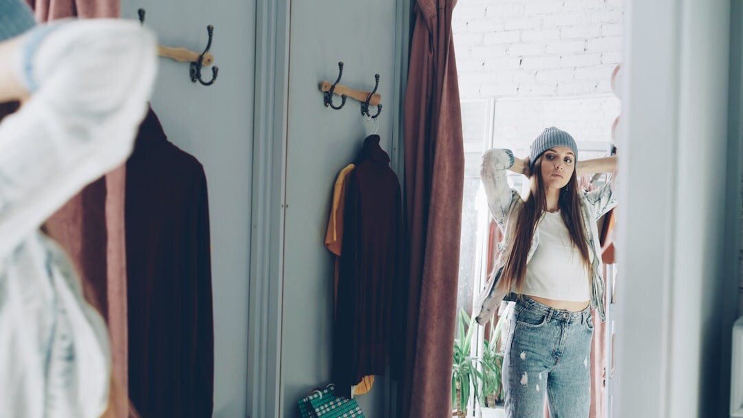 Dressing room mirror surrounded by lights with a garment rack nearby